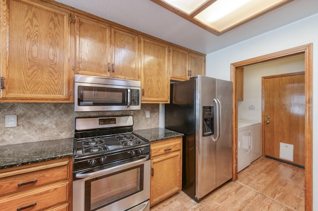 689 E Pintail Cir, Fresno, CA 93730 - kitchen with appliances with stainless steel finishes, independent washer and dryer, light wood-style floors, tasteful backsplash, and dark stone countertops