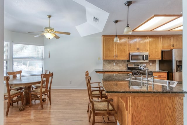 689 E Pintail Cir, Fresno, CA 93730 - kitchen featuring appliances with stainless steel finishes, ceiling fan, light wood-style flooring, backsplash, and dark stone countertops