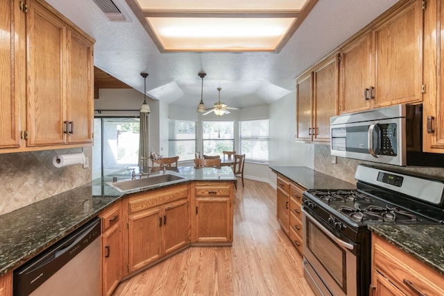 689 E Pintail Cir, Fresno, CA 93730 - kitchen with stainless steel appliances, light wood finished floors, a peninsula, a ceiling fan, and brown cabinets