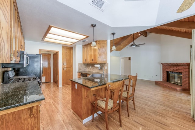 689 E Pintail Cir, Fresno, CA 93730 - kitchen featuring light wood-style flooring, a peninsula, backsplash, a breakfast bar area, and dark stone counters