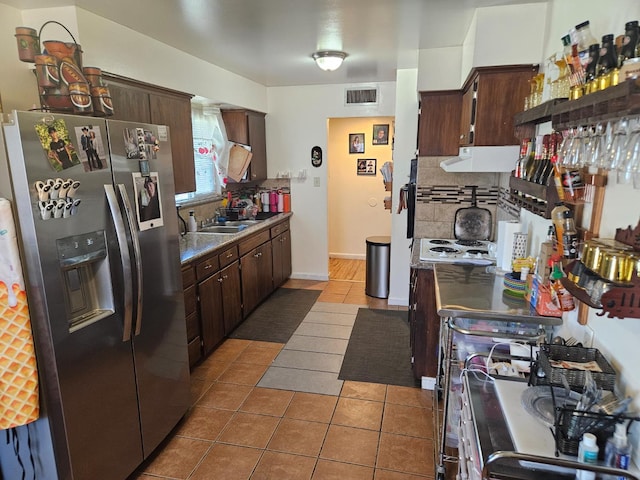 432 Brimmer Rd, Merced, CA 95341 - kitchen featuring stainless steel refrigerator with ice dispenser, under cabinet range hood, decorative backsplash, and dark brown cabinetry