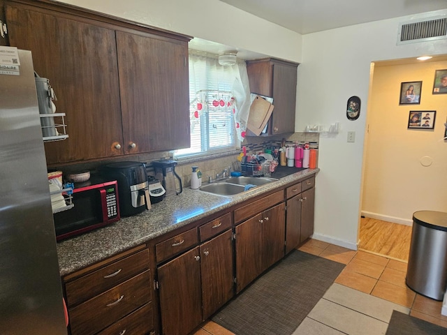 432 Brimmer Rd, Merced, CA 95341 - kitchen featuring freestanding refrigerator, backsplash, light tile patterned floors, and dark brown cabinetry