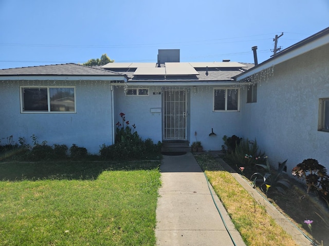 432 Brimmer Rd, Merced, CA 95341 - view of front of house featuring a front lawn, solar panels, stucco siding, and a shingled roof