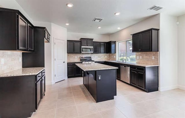2166 Junipero Ave, Clovis, CA 93619 - kitchen with stainless steel appliances, a center island, decorative backsplash, recessed lighting, and light tile patterned floors