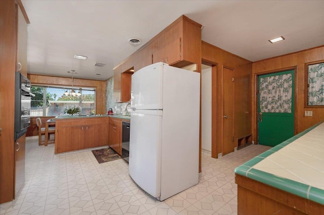 5481 E Geary St, Fresno, CA 93727 - kitchen with black appliances, wood walls, light floors, brown cabinets, and a chandelier