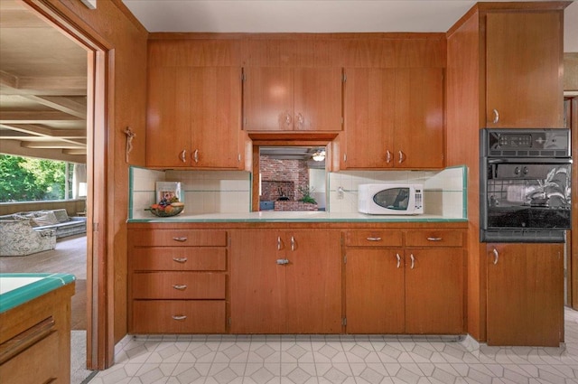 5481 E Geary St, Fresno, CA 93727 - kitchen featuring black oven, white microwave, brown cabinetry, and tasteful backsplash