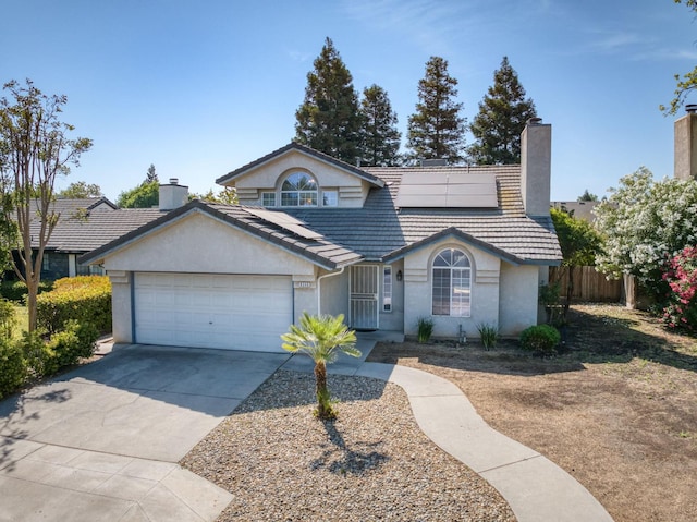 9340 N Jackson Ave, Fresno, CA 93720 - view of front of home featuring a chimney, a garage, solar panels, driveway, and stucco siding