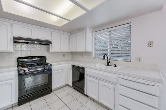 9340 N Jackson Ave, Fresno, CA 93720 - kitchen with black appliances, under cabinet range hood, tile countertops, white cabinets, and light tile patterned flooring