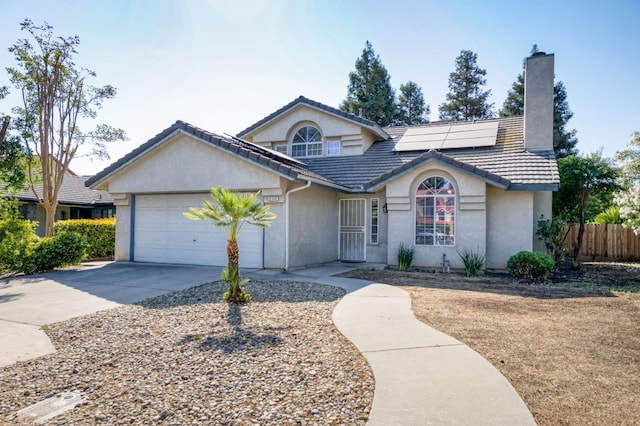 9340 N Jackson Ave, Fresno, CA 93720 - view of front of home featuring a chimney, stucco siding, concrete driveway, an attached garage, and roof mounted solar panels