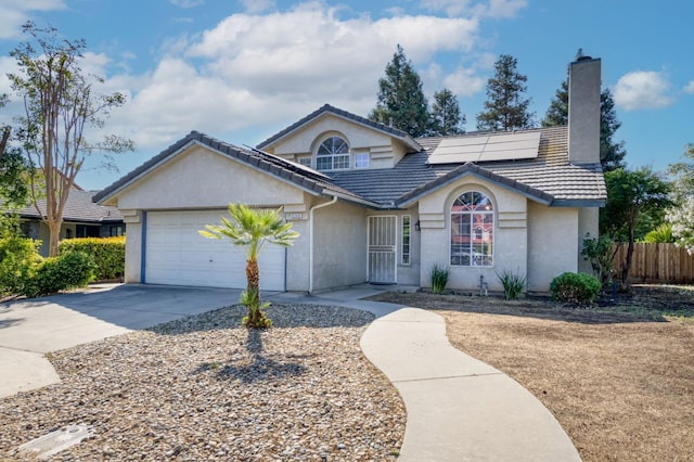 9340 N Jackson Ave, Fresno, CA 93720 - ranch-style house with stucco siding, a chimney, driveway, a garage, and roof mounted solar panels