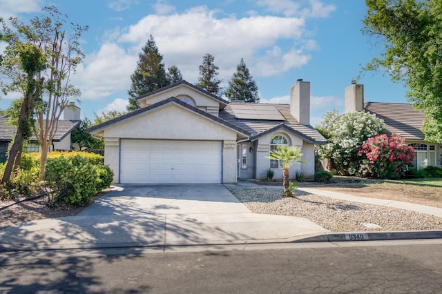 9340 N Jackson Ave, Fresno, CA 93720 - single story home with driveway, an attached garage, solar panels, stucco siding, and a chimney