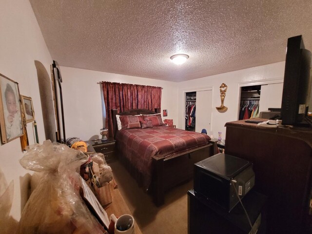 bedroom with a textured ceiling and two closets