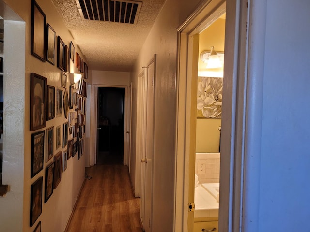 corridor featuring dark wood-style flooring and a textured ceiling