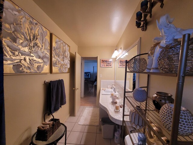 hall featuring light tile patterned flooring and a sink