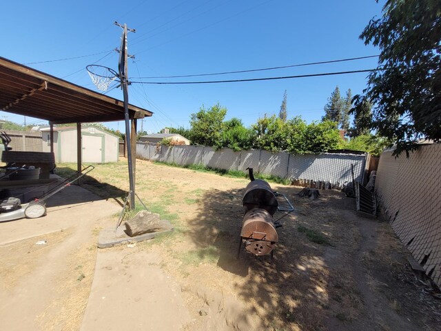 fenced backyard with a shed and an outdoor fire pit