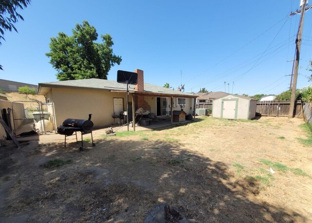 back of property featuring a shed, a fenced backyard, a chimney, stucco siding, and a patio area