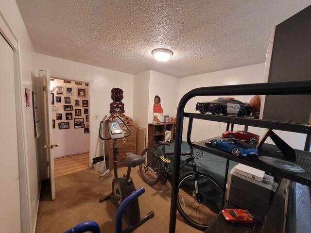 exercise area featuring a textured ceiling and carpet