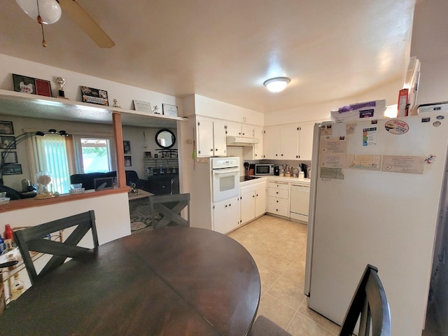 kitchen with white appliances, under cabinet range hood, light tile patterned floors, ceiling fan, and white cabinetry