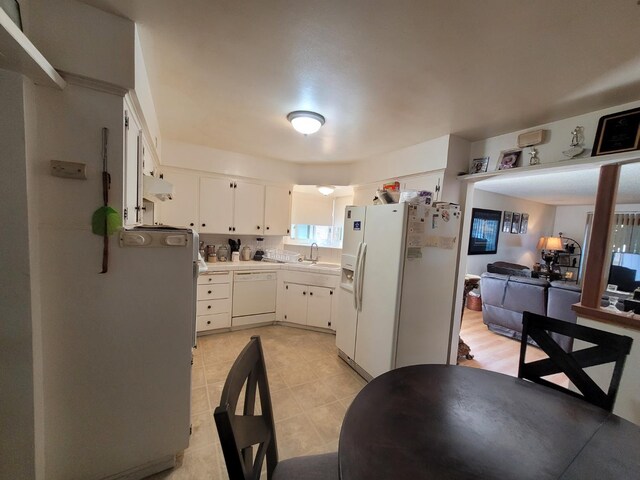 kitchen with white appliances, white cabinetry, light tile patterned floors, light countertops, and open floor plan