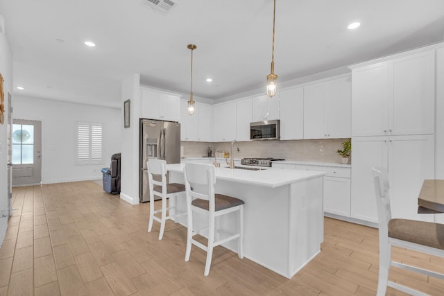 6569 E Lyell Ave, Fresno, CA 93727 - kitchen with stainless steel appliances, light countertops, tasteful backsplash, light wood finished floors, and a breakfast bar area