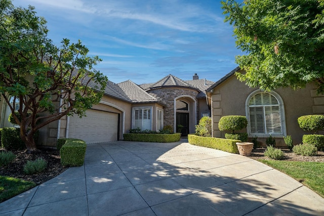 1622 E Shadow Crk, Fresno, CA 93730 - view of front of house with stone siding, driveway, stucco siding, an attached garage, and a chimney
