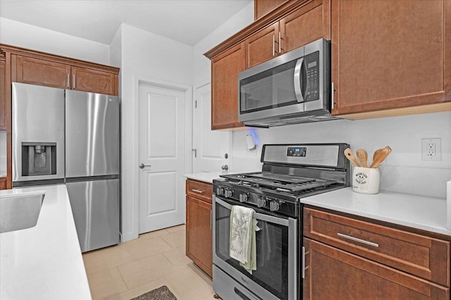 6105 W Richert Ave, Fresno, CA 93723 - kitchen featuring stainless steel appliances, light countertops, light tile patterned flooring, and brown cabinets