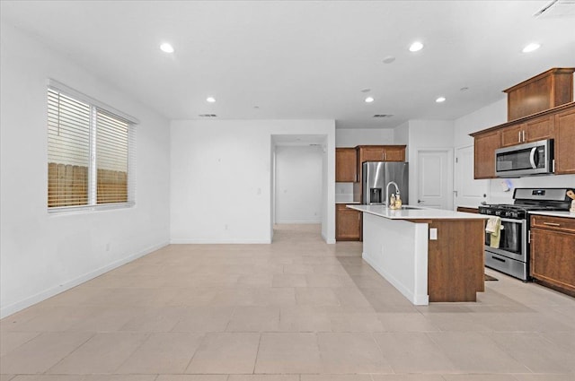 6105 W Richert Ave, Fresno, CA 93723 - kitchen with stainless steel appliances, recessed lighting, light countertops, a center island with sink, and brown cabinetry