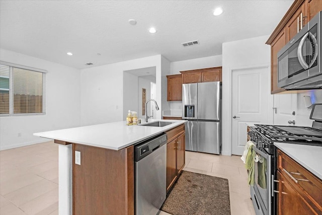 6105 W Richert Ave, Fresno, CA 93723 - kitchen with stainless steel appliances, a kitchen island with sink, light tile patterned floors, light countertops, and brown cabinets