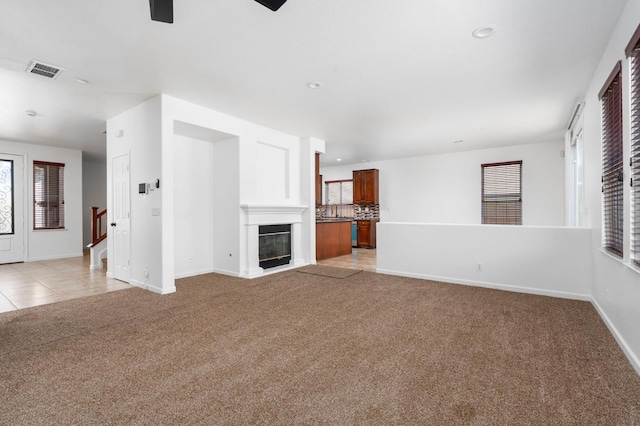 5227 E Florence Ave, Fresno, CA 93727 - unfurnished living room featuring light carpet, recessed lighting, a glass covered fireplace, a ceiling fan, and light tile patterned flooring