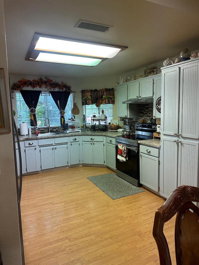6675 N Lola Ave, Fresno, CA 93722 - kitchen featuring stainless steel electric range oven, light wood-style floors, under cabinet range hood, backsplash, and green cabinetry
