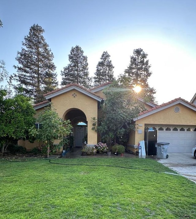 6675 N Lola Ave, Fresno, CA 93722 - mediterranean / spanish home with stucco siding, a front yard, and an attached garage