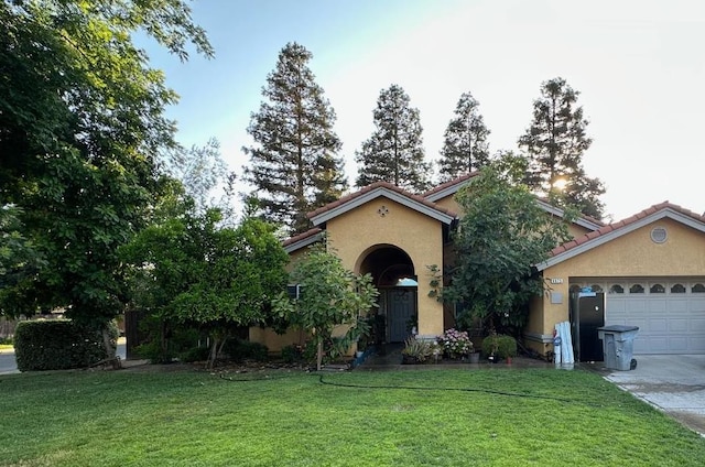 6675 N Lola Ave, Fresno, CA 93722 - mediterranean / spanish house featuring stucco siding, a front lawn, concrete driveway, a tile roof, and an attached garage