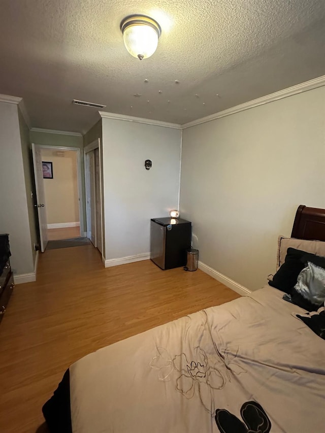 6675 N Lola Ave, Fresno, CA 93722 - bedroom with light wood finished floors, a textured ceiling, and ornamental molding