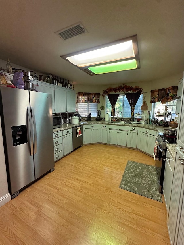 6675 N Lola Ave, Fresno, CA 93722 - kitchen featuring appliances with stainless steel finishes, green cabinets, and light wood-type flooring