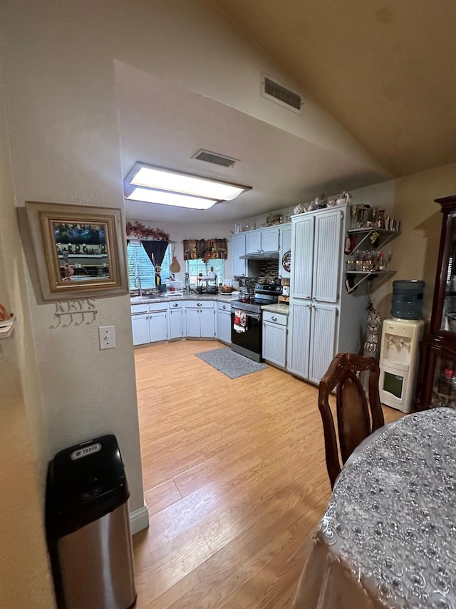 6675 N Lola Ave, Fresno, CA 93722 - kitchen featuring stainless steel electric range, light wood-style flooring, lofted ceiling, and light countertops