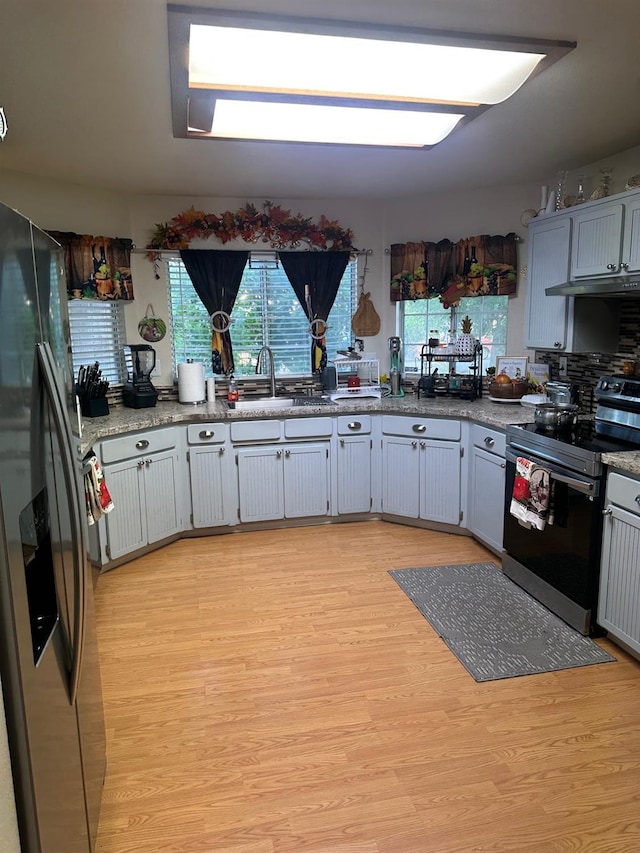 6675 N Lola Ave, Fresno, CA 93722 - kitchen featuring appliances with stainless steel finishes, under cabinet range hood, and light wood finished floors