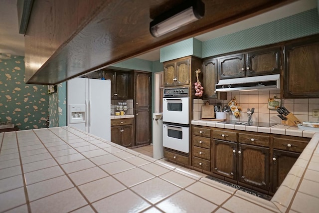 5513 N El Adobe Dr, Fresno, CA 93711 - kitchen with white appliances, under cabinet range hood, tile countertops, wallpapered walls, and backsplash