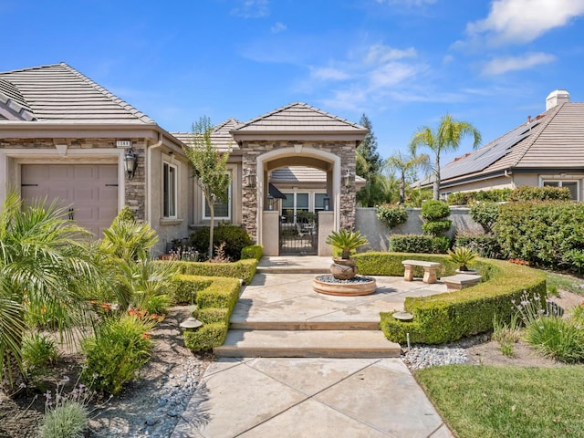 1568 E Sterling Hill Way, Fresno, CA 93730 - doorway to property featuring a tile roof, a gate, stone siding, and a garage