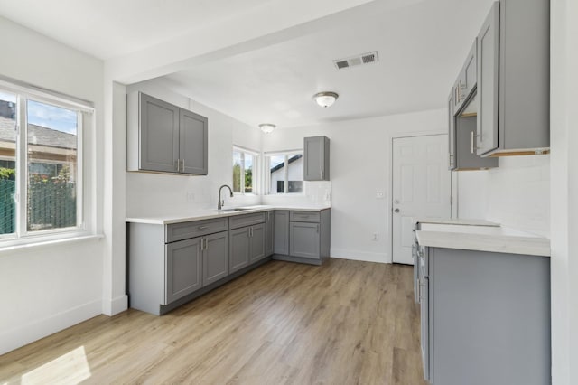 4752 E Kerckhoff Ave, Fresno, CA 93702 - kitchen featuring gray cabinets, healthy amount of natural light, light wood-style flooring, and light countertops