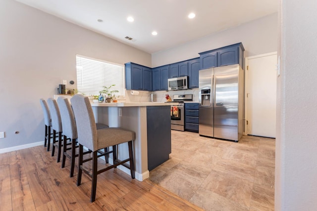 1774 Castle Way, Lemoore, CA 93245 - kitchen featuring stainless steel appliances, blue cabinets, a kitchen breakfast bar, a peninsula, and light countertops