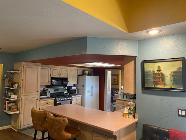 36883 Cloverleaf Ave, Madera, CA 93636 - kitchen featuring appliances with stainless steel finishes, a textured wall, a breakfast bar area, a peninsula, and light countertops