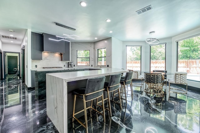 1292 E Valley Forge Dr, Fresno, CA 93720 - kitchen featuring wall chimney range hood, healthy amount of natural light, recessed lighting, backsplash, and a breakfast bar area