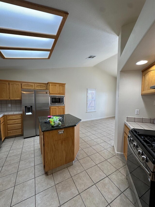 220 S Double Tree Way, Madera, CA 93637 - kitchen featuring stainless steel appliances, light tile patterned floors, vaulted ceiling, a center island, and tile counters
