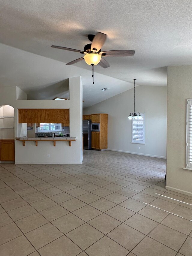 220 S Double Tree Way, Madera, CA 93637 - unfurnished living room with vaulted ceiling, light tile patterned flooring, ceiling fan, and a textured ceiling