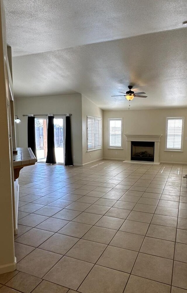 220 S Double Tree Way, Madera, CA 93637 - unfurnished living room featuring a textured ceiling, light tile patterned flooring, a ceiling fan, and a fireplace