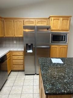 220 S Double Tree Way, Madera, CA 93637 - kitchen featuring appliances with stainless steel finishes, light tile patterned flooring, decorative backsplash, and dark stone countertops