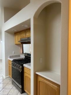 220 S Double Tree Way, Madera, CA 93637 - kitchen featuring black range with gas stovetop, under cabinet range hood, light tile patterned flooring, light countertops, and arched walkways