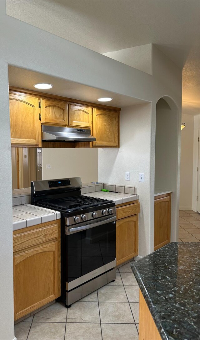 220 S Double Tree Way, Madera, CA 93637 - kitchen with stainless steel range with gas cooktop, under cabinet range hood, light tile patterned floors, tile countertops, and arched walkways