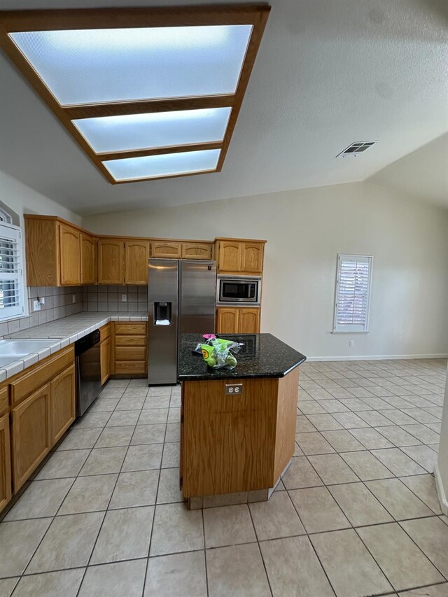 220 S Double Tree Way, Madera, CA 93637 - kitchen with stainless steel appliances, lofted ceiling, light tile patterned floors, tasteful backsplash, and a kitchen island