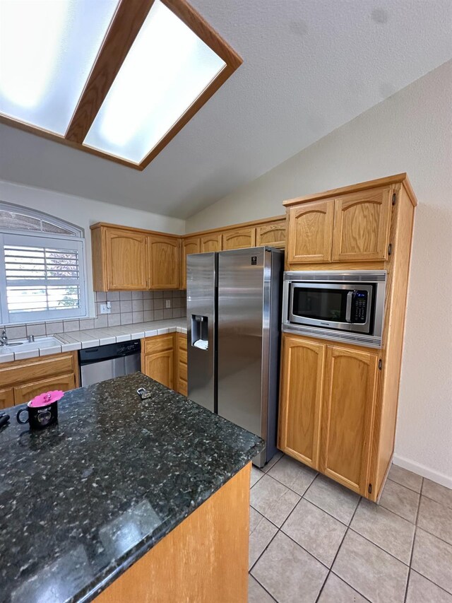 220 S Double Tree Way, Madera, CA 93637 - kitchen featuring stainless steel appliances, vaulted ceiling, light tile patterned floors, and backsplash